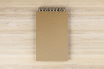 Top view and close up of brown spring note pad on wooden desktop background. Mock up place for your advertisement. Education, work, supplies and stationery concept. 3D Rendering.