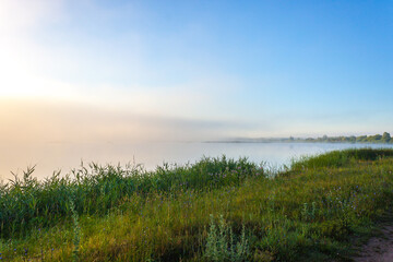 Fototapeta na wymiar Landscape of lake in mist with sun glow at sunrise