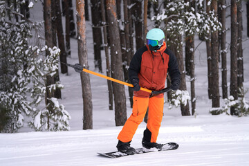 Winter sports recreation. A snowboarder climbs uphill on a rope lift. Copy space.