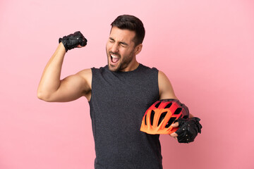 Young cyclist man isolated on pink background doing strong gesture