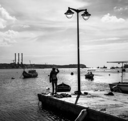 Early morning on the Marsaxlokk waterfront. View of the sea and boats Luzza. Malta. Black and white.