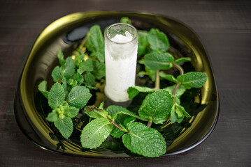 Cherry liqueur with mint and lemon on a black plate with ice
