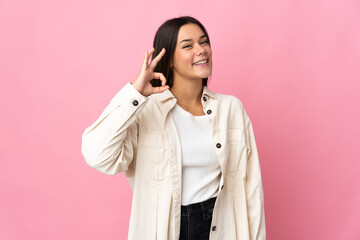 Teenager girl isolated on pink background showing ok sign with fingers