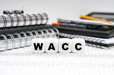 On the table, among office objects, cubes with the inscription - WACC