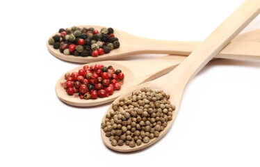 Coriander, red and colorful pepper in wooden spoon isolated on white  
