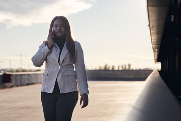 Obraz premium businesswoman talking on smartphone. African american woman in white plaid.
