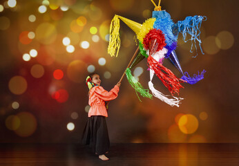 Mexican girl breaking a piñata in a Christmas inn with bright lights suna traditions of the...