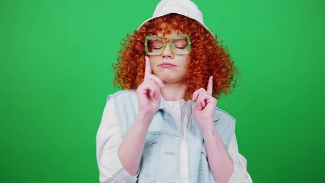 Surprise. Young happy redhead lady jumping into shot and showing gotcha gesture to camera, chroma key background