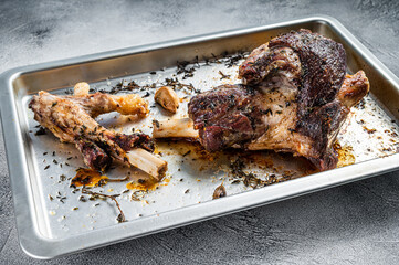 Roasted lamb mutton whole leg in a baking dish. White background. Top view