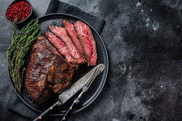 Grilled hanger or Onglet beef meat steak on a plate with thyme. Black background. Top View. Copy...