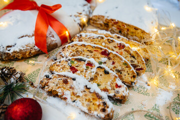 Traditional Christmas stollen made of dried fruits and nuts sprinkled with powdered sugar on the...