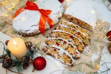 Traditional Christmas stollen made of dried fruits and nuts sprinkled with powdered sugar on the...