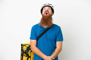 Young reddish caucasian man with thermal backpack isolate don white background looking up and with surprised expression