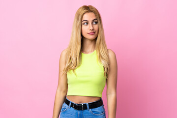 Young Uruguayan blonde woman over isolated pink background making doubts gesture looking side