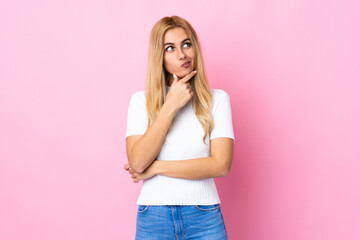 Young Uruguayan blonde woman over isolated pink background and looking up