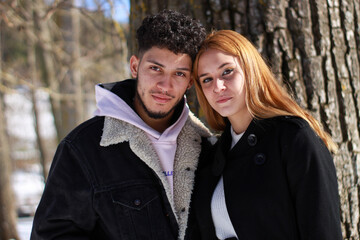 portrait of young interracial couple looking at camera, natural horizontal background