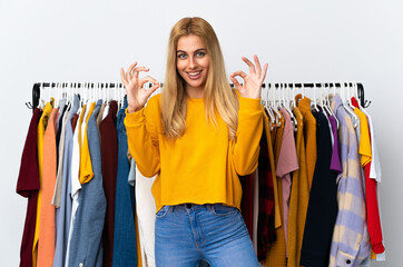 Young Uruguayan blonde woman in a clothing store showing an ok sign with fingers