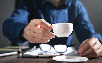 Fototapeta na wymiar Businessman working in office and holding a cup of coffee.
