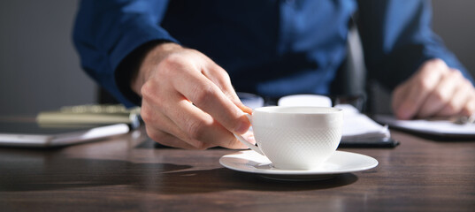 Businessman working in office and holding a cup of coffee.