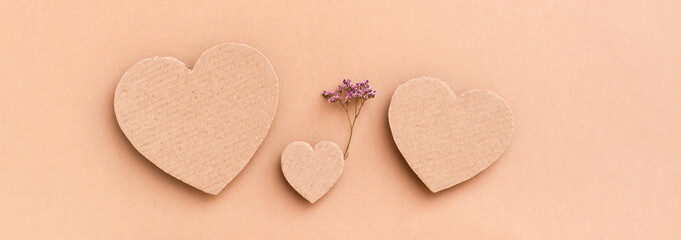 Obraz premium Family concept. Three cardboard hearts - a child with a dry flower between parents on a beige background. Top view. Web banner