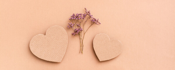 Date concept. Two cardboard hearts and a bouquet of dried flowers between them on a beige background. Top view. Web  banner