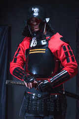 Man in ancient samurai armor holding a Japanese sword Katana