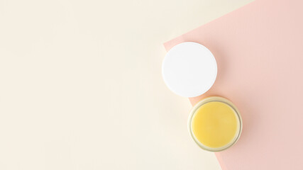 An open jar with Lanolin, a grease from sheep wool. Acts as a skin ointment, water-proofing wax, and for washing laundry. on a minimalistic pink background. Skincare concept. Copy Space. Top view