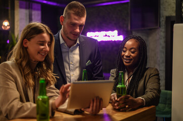 Cheerful colleagues drinking beer in the bar together after work