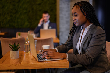 African american businesswoman working on her laptop while drinking coffee in a cafe