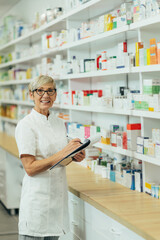 Beautiful senior female pharmacist checking medications on a shelf