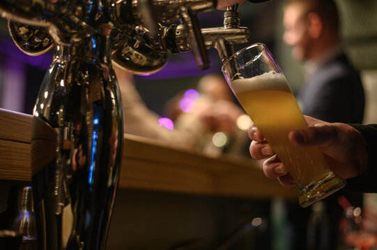 Hand of bartender using beer tap while working in a bar