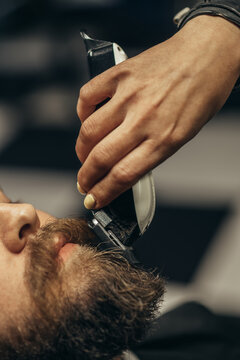 Young bearded man getting beard haircut by hairdresser