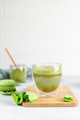 Japanese matcha green tea in thermal glasses and macaroon cake on a wooden stand. Close-up, on a gray background, vertical