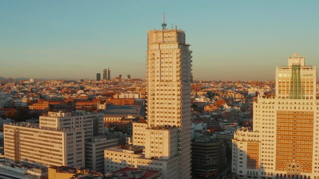 Forwards rising footage of old high rise buildings at Spain square with cityscape in background at sunset time.