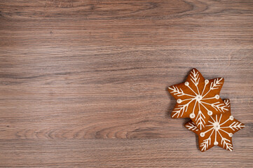 Two gingerbread stars with white glaze and silver beads on a wooden table. Copy space.