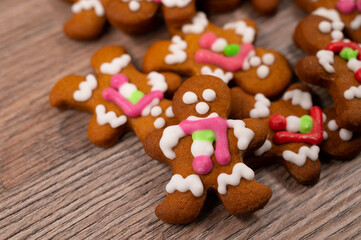 Close-up of a pile of gingerbread men with a white glaze on a wooden table.