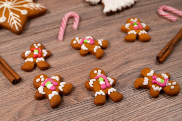 Close-up of men's gingerbread men on a wooden table with Christmas candies and cinnamon sticks.