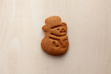 snowman gingerbread cookie on white wooden background