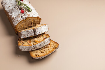 Fresh sliced Christmas muffin with dried fruits and nuts on a beige background minimalism