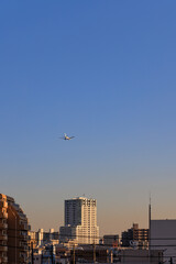 夕焼けの都市の上空を飛ぶ旅客機