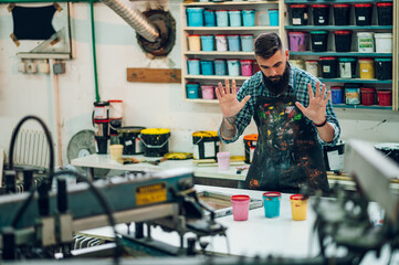 Male worker mixing colors for screen printing in a workshop