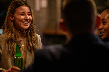 Woman drinking beer in the bar with her colleagues after work