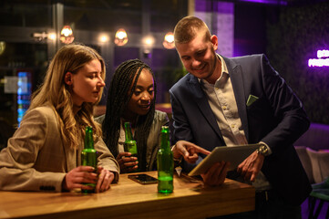 Cheerful colleagues drinking beer in the bar together after work
