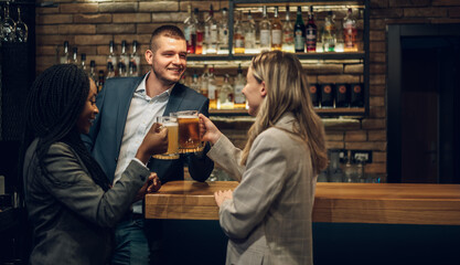 Cheerful colleagues drinking beer in the bar together after work