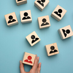 female hand holds a wooden block on a blue background. Recruitment concept, teamwork, effective management