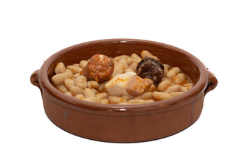 Close up of a terracotta dish with Asturian fabada, a typical Spanish bean stew, on a white background.