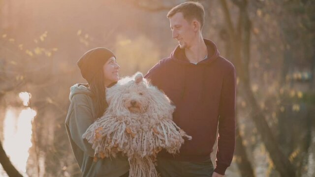 Happy Couple with Dog. Young Caucasian Couple Holding Hungarian Shepherd Dog Puli On Hands.
