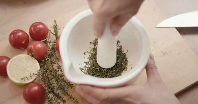 Hand grind crush thyme spice ingredient pestle and mortar in close up