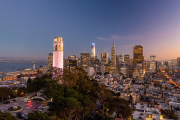 Obraz premium Nighttime aerial view of the San Francisco skyline with Coit Tower prominent in the frame. Bay Bridge in the background.