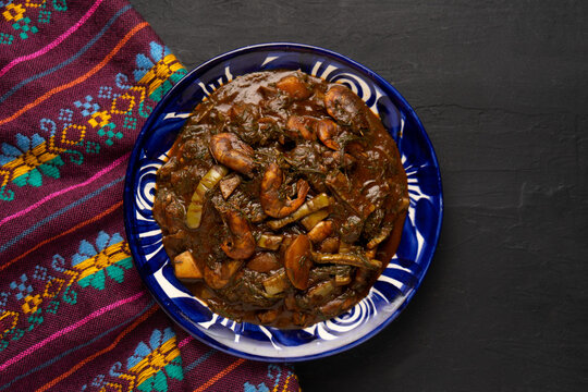Mexican romeritos with mole sauce and shrimp on a dark background